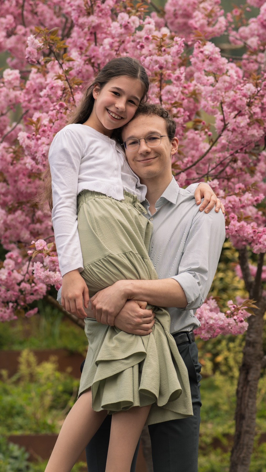 Vater mit Tochter vor rosa Blüten