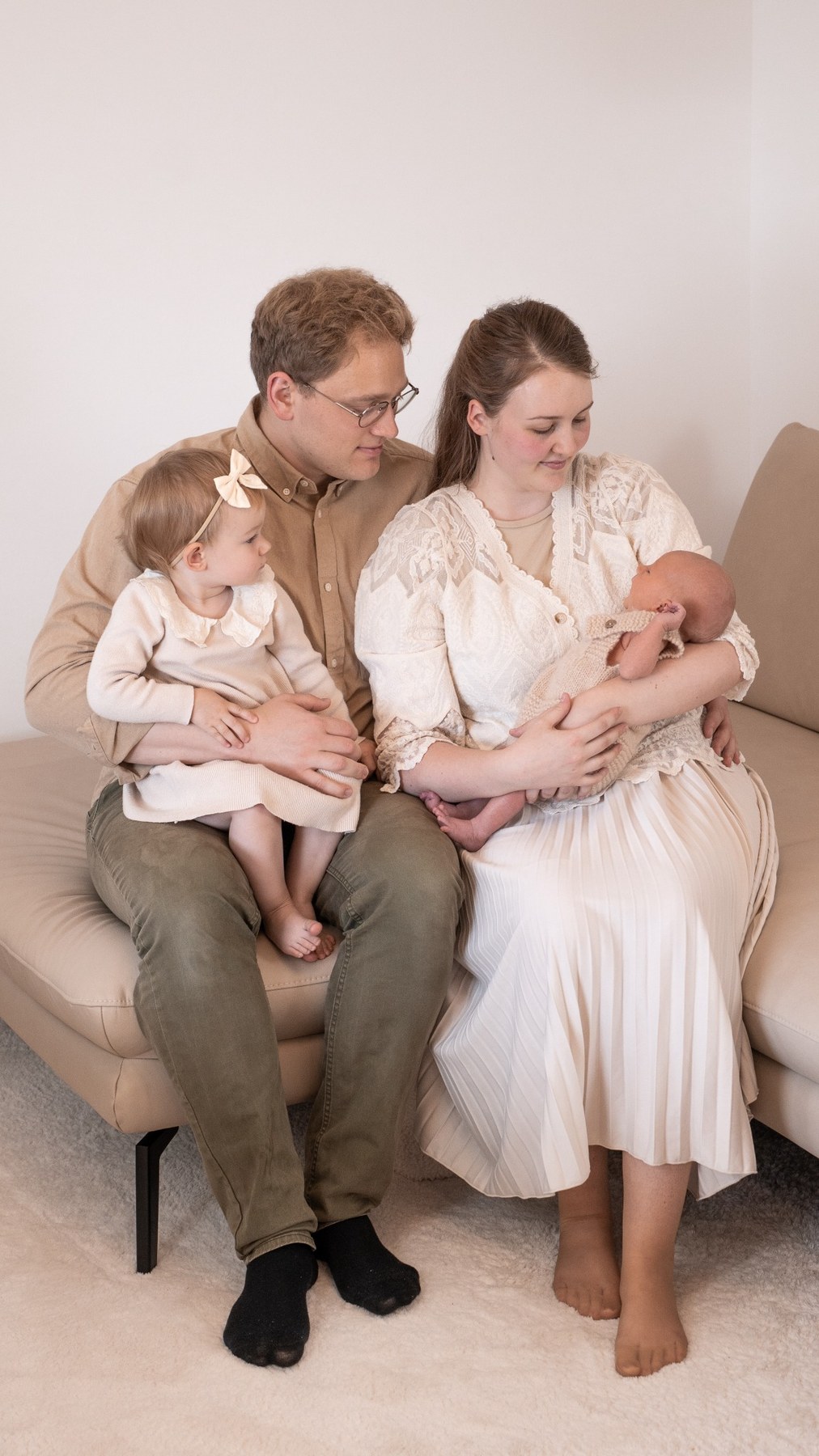 Familie mit Neugeborenem auf einem hellen Sofa