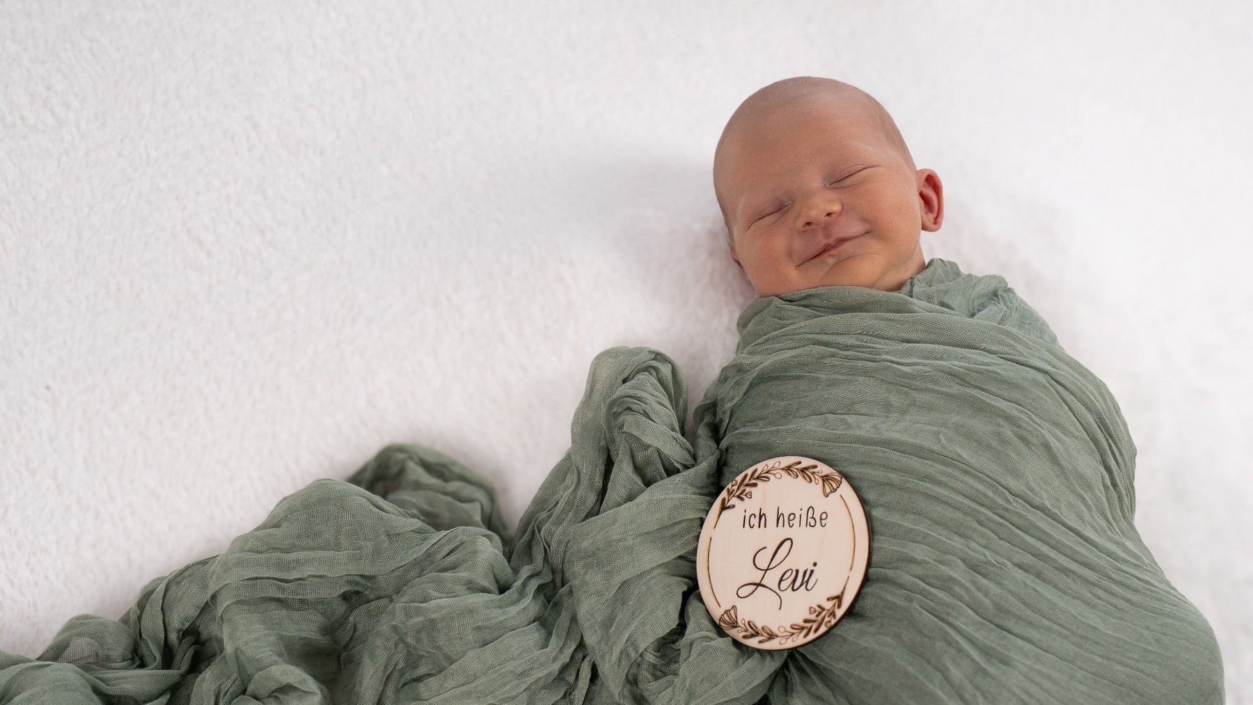 Neugeborenes Baby in grünem Tuch